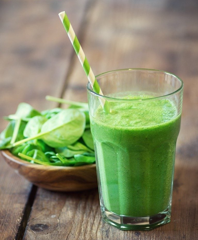 Green Breakfast Smoothie, leaves in a wooden bowl in wooden background