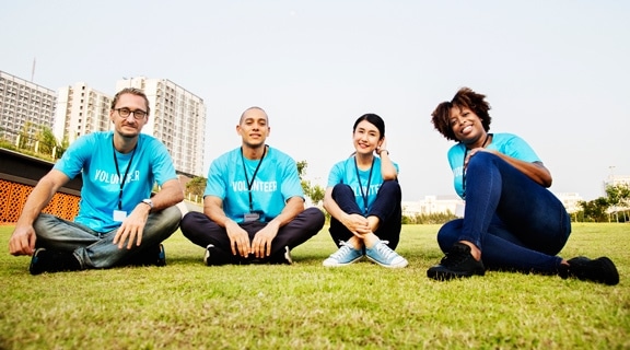 2 girls and 2 boys are wearing the same shirt sitting on the grass