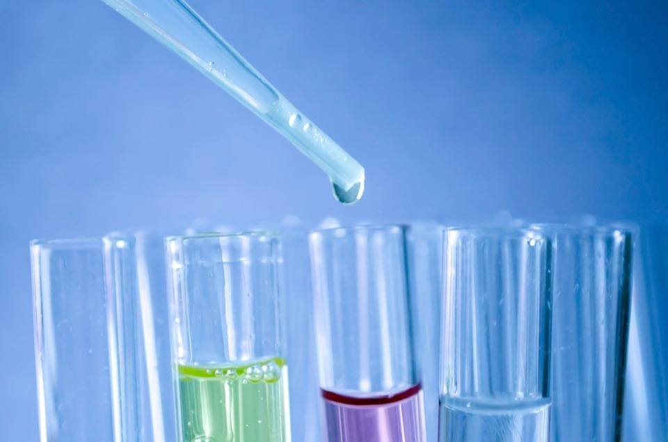 A dropper transferring chemicals to the test tube in blue background.