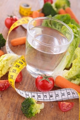 Glass of water, measuring tape, vegetables placed on the wooden table