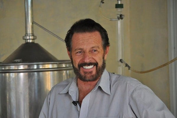 A man smiling beside the machines for making essential oils