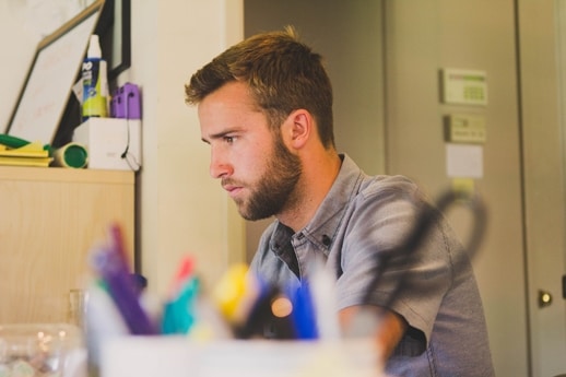 A man wears gray polo shirt inside an office or a room. Man concentration