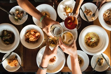 Group of friends drinking alcohol and a bunch of food at the table