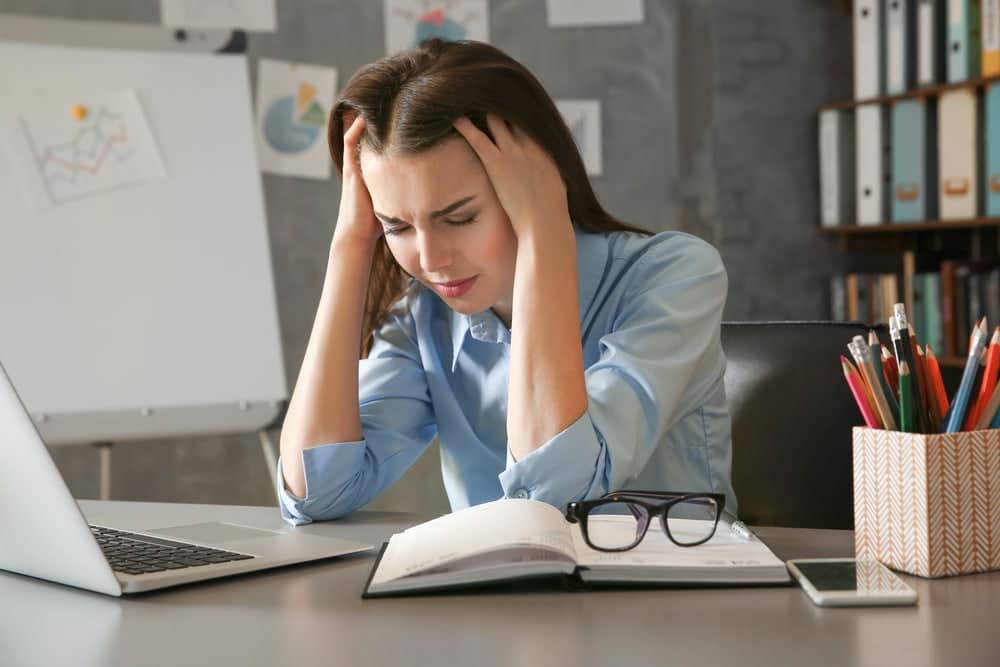 Beautiful young woman suffering from headache while working in office