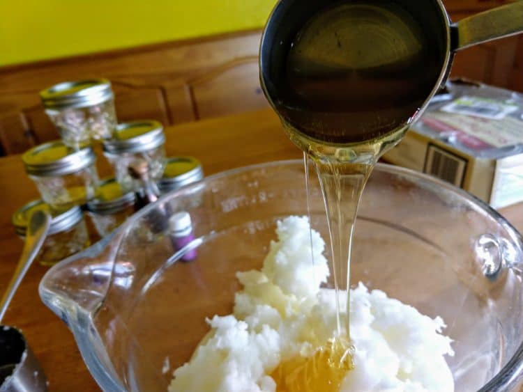 Tablespoon dropping honey in a bowl, jars in the table, wooden table surface