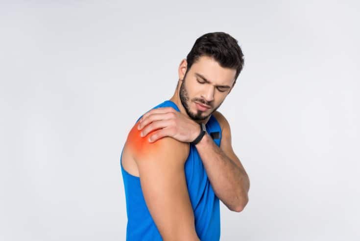 Man with blue shirt having shoulder pain in plain white background