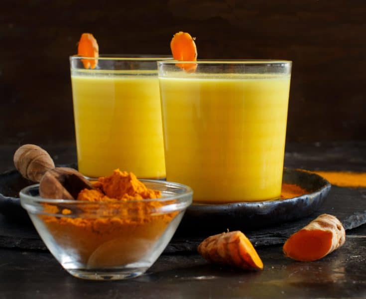 Golden milk with turmeric powder in a glass close up