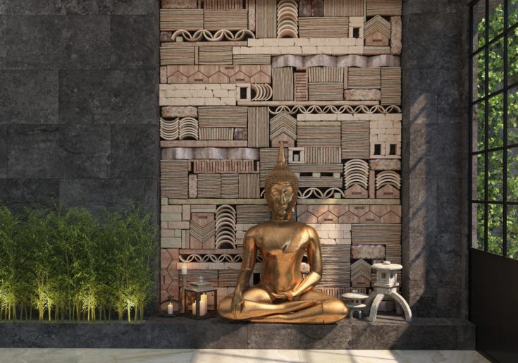 This praying corner shows a statue of Buddha, surrounded by candles and natural plants, against a black wall with asymmetric patterns.