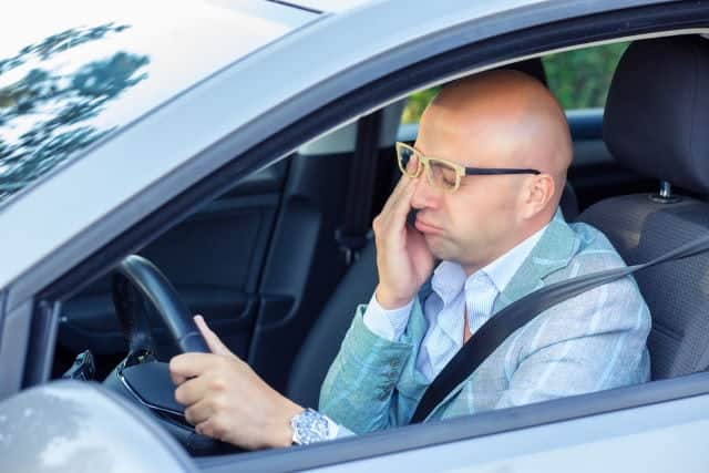 Tired at he wheel. Sleepy fatigued exhausted young man driving his car in traffic after long hour drive. Transportation sleep deprivation accident concept