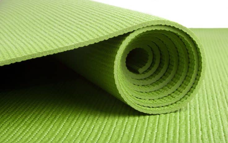 A green yoga/pilates/exercise mat rolled up on white