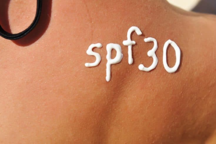 Sunscreen lotion over tan woman skin made as SPF 30 word