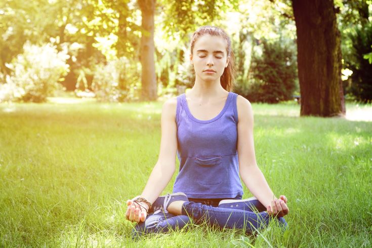 beautiful teenage girl meditates in nature