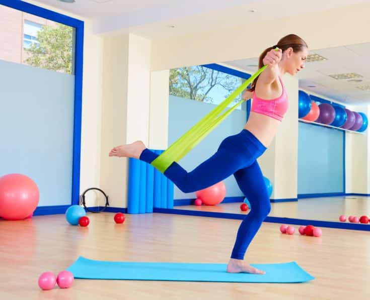 Pilates woman standing rubber band exercise workout at gym indoor